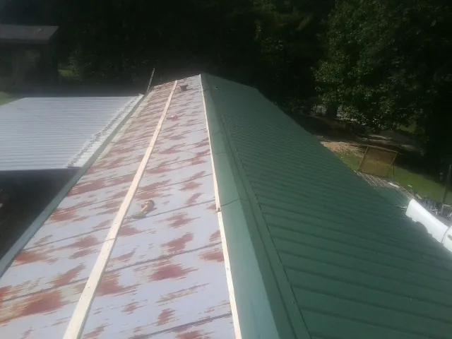 Old rusted panels beside newly installed green metal roofing — Wind Damage Roof Repair by Roofing Brothers in Jeffersonville