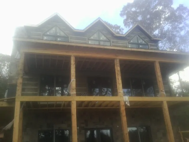 Dormers and porch framing on a large log home under construction — Roof Coating work by our crew in Jeffersonville