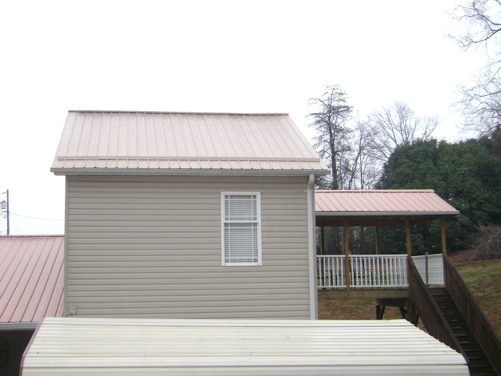 Tan metal roofs on a two story addition and attached porch, from a Roof Replacement job in Jeffersonville